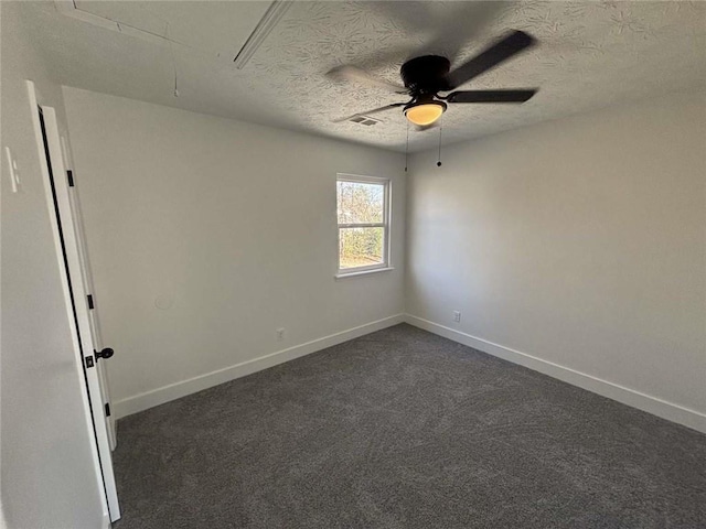 unfurnished room with visible vents, baseboards, ceiling fan, attic access, and dark colored carpet