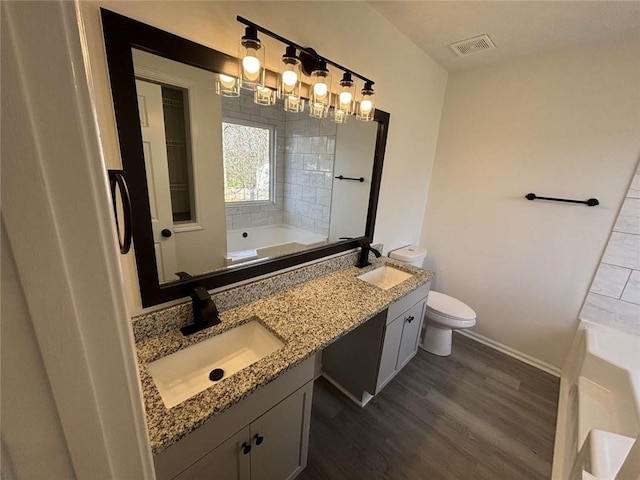 bathroom with a sink, visible vents, a bathing tub, and wood finished floors