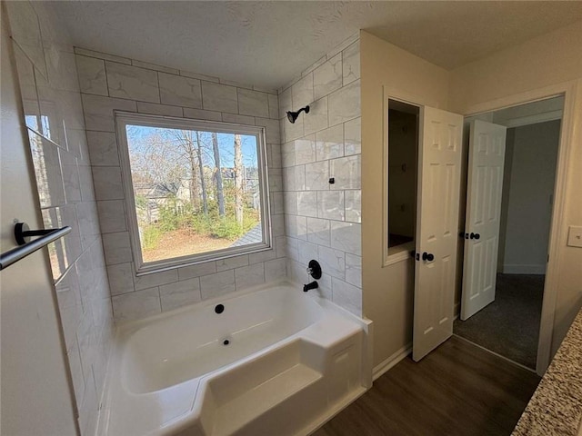 bathroom with wood finished floors, baseboards, and a textured ceiling