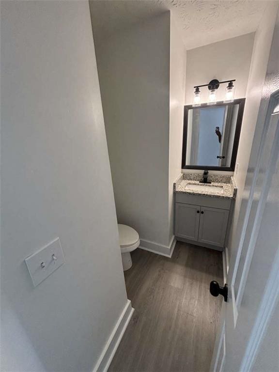 bathroom featuring vanity, wood finished floors, baseboards, a textured ceiling, and toilet