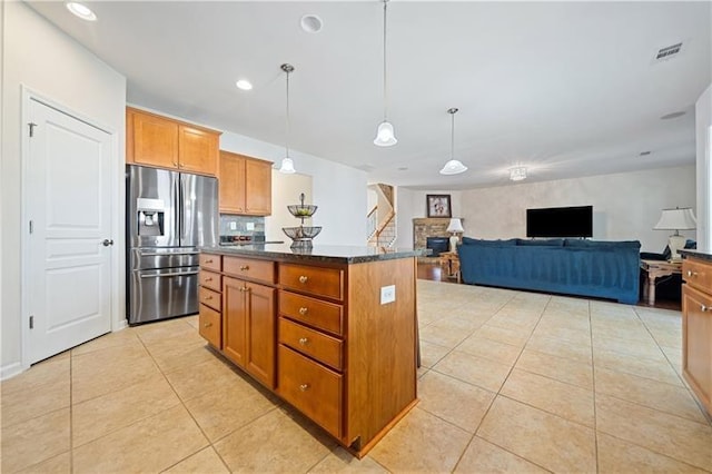 kitchen featuring visible vents, light tile patterned floors, a center island, stainless steel fridge, and brown cabinetry
