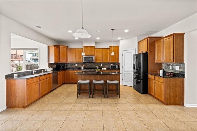 kitchen with brown cabinetry, backsplash, appliances with stainless steel finishes, and a sink