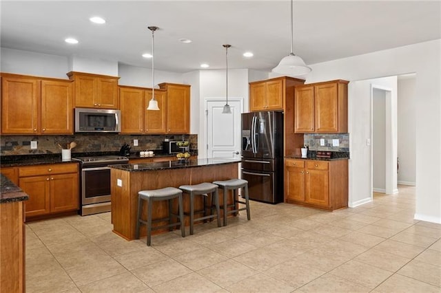 kitchen featuring brown cabinets, a breakfast bar, backsplash, appliances with stainless steel finishes, and a kitchen island
