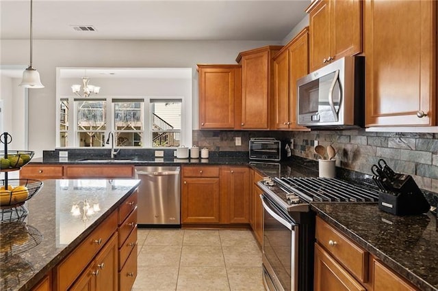 kitchen featuring brown cabinets, backsplash, visible vents, a sink, and appliances with stainless steel finishes