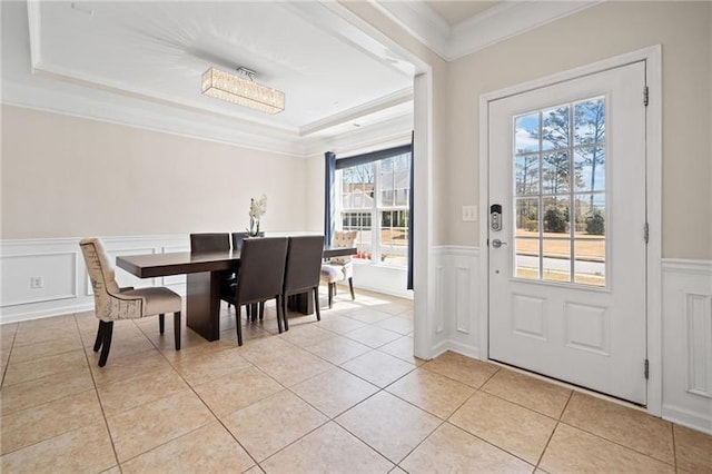 dining room featuring a wainscoted wall, a decorative wall, ornamental molding, and light tile patterned flooring