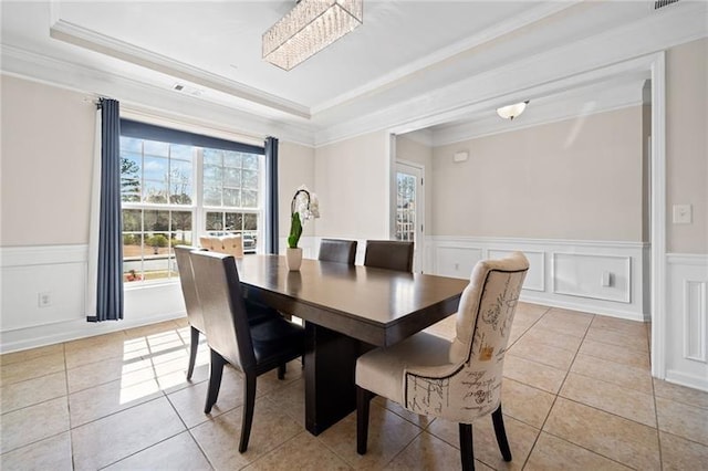 dining space featuring light tile patterned floors, ornamental molding, and a raised ceiling