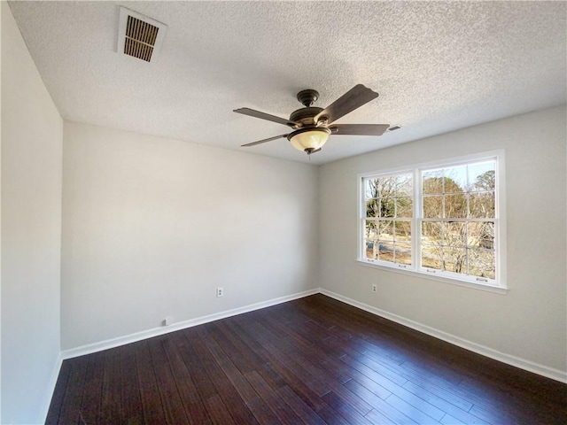 empty room with ceiling fan, dark wood-type flooring, and a textured ceiling