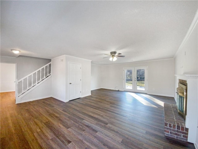 unfurnished living room with french doors, a brick fireplace, ornamental molding, ceiling fan, and dark hardwood / wood-style floors