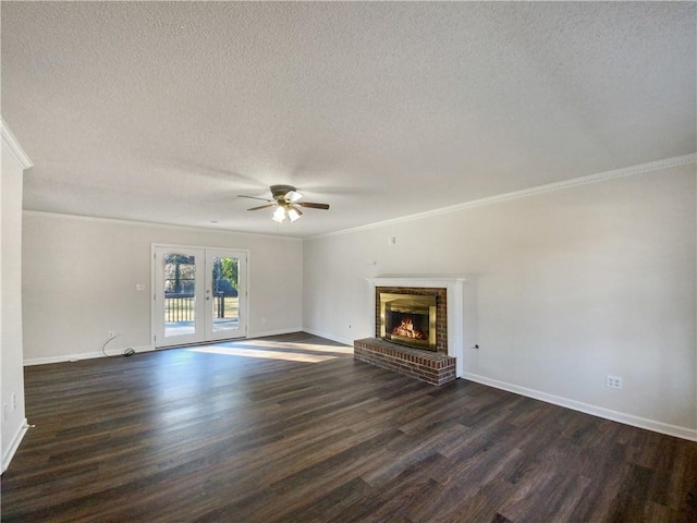 unfurnished living room featuring ceiling fan, dark wood-type flooring, a brick fireplace, crown molding, and a textured ceiling