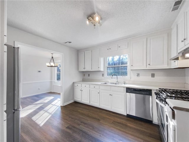 kitchen with appliances with stainless steel finishes, dark wood-type flooring, sink, pendant lighting, and white cabinets