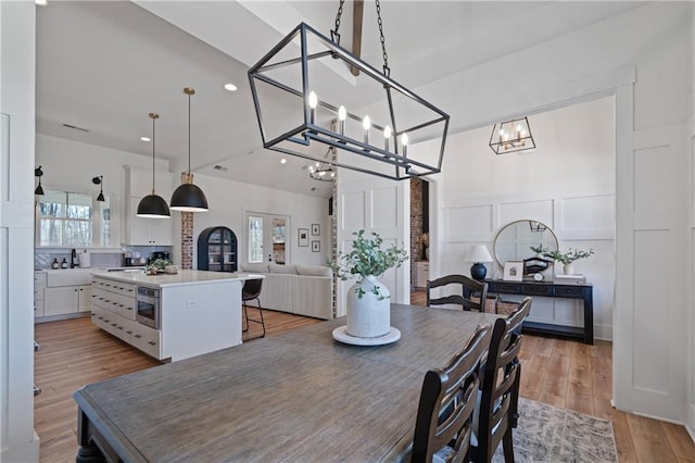 dining space with recessed lighting, a wainscoted wall, light wood-style flooring, and a decorative wall