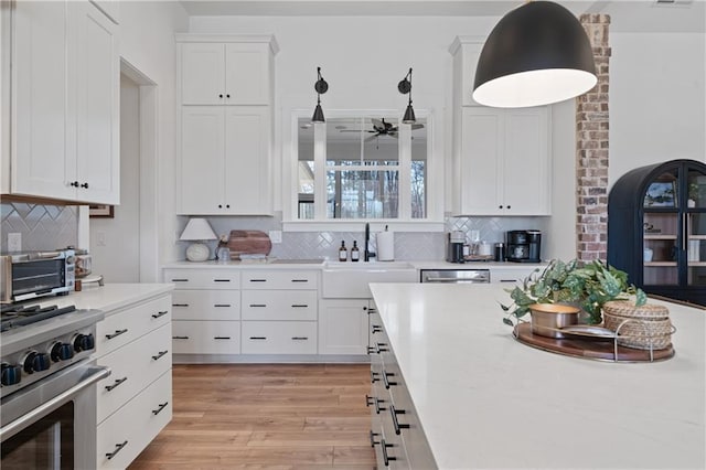 kitchen featuring light countertops, light wood-style flooring, appliances with stainless steel finishes, white cabinets, and a sink