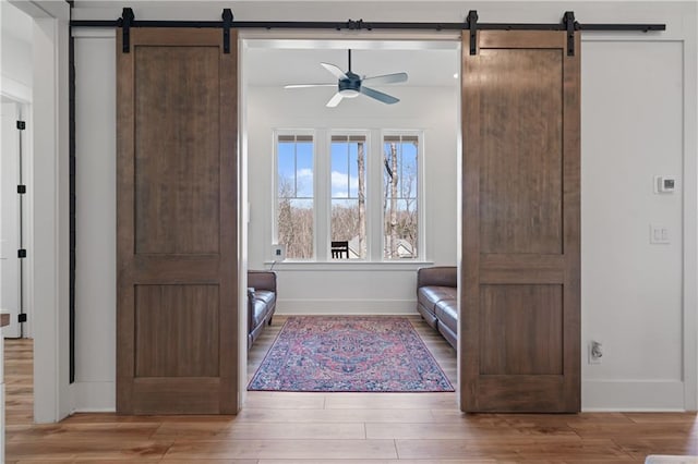 unfurnished room featuring baseboards, a barn door, and wood finished floors