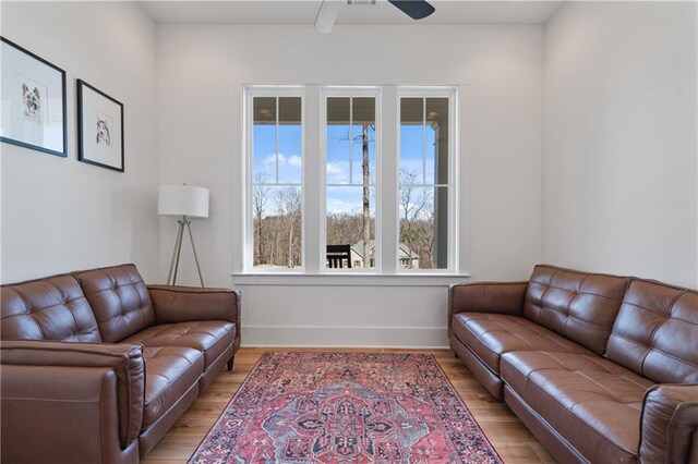 living room featuring light wood-type flooring, baseboards, and ceiling fan