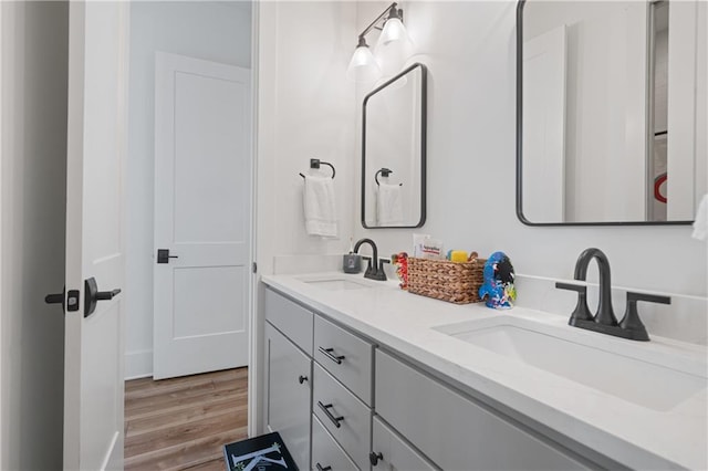 full bath featuring double vanity, wood finished floors, and a sink