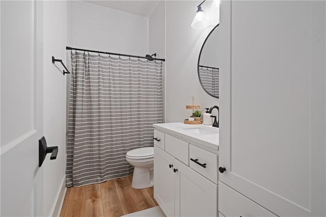 bathroom with a shower with curtain, toilet, wood finished floors, and vanity