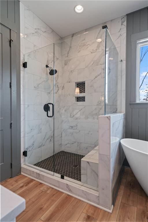 full bath featuring recessed lighting, a shower stall, wood finished floors, and a freestanding tub