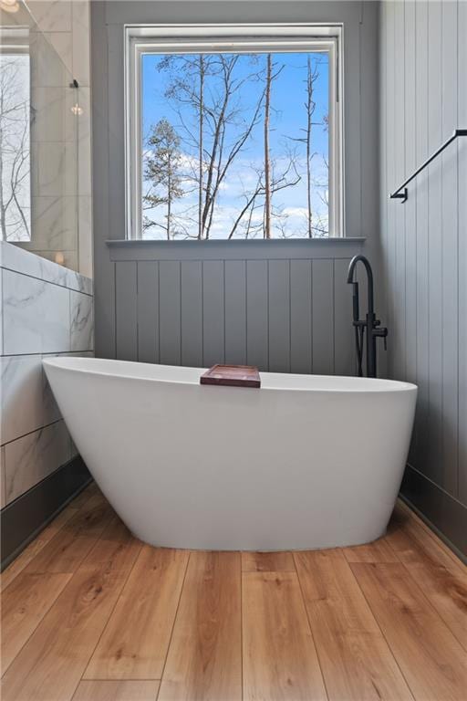 bathroom featuring hardwood / wood-style flooring and a freestanding tub