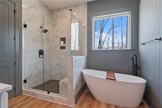 full bath featuring a shower stall, wood finished floors, and a freestanding bath