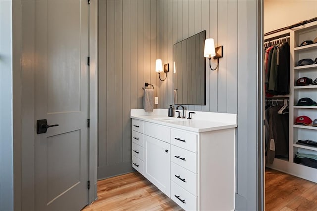 bathroom with a walk in closet, wood finished floors, and vanity