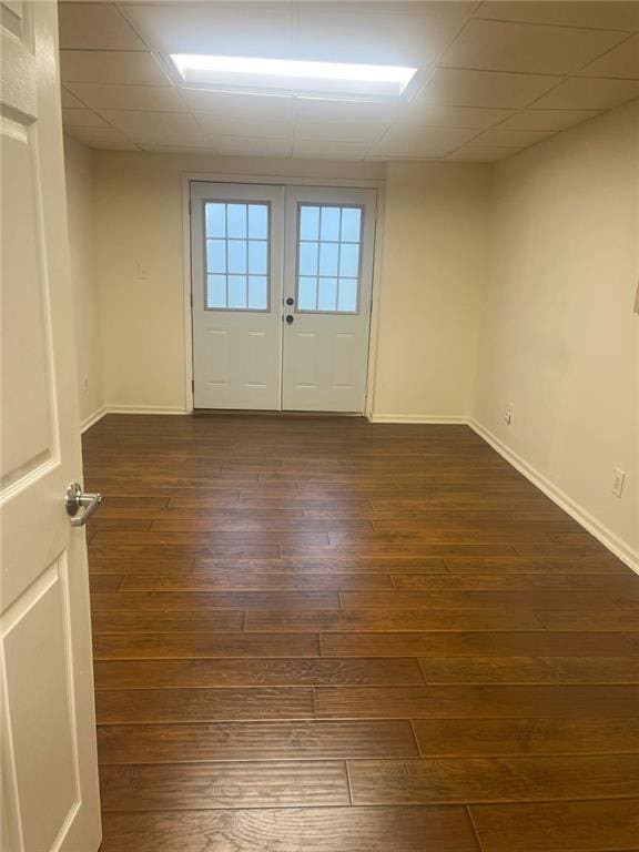 spare room with a drop ceiling and dark wood-type flooring