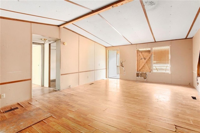 empty room featuring visible vents, hardwood / wood-style floors, and vaulted ceiling with beams