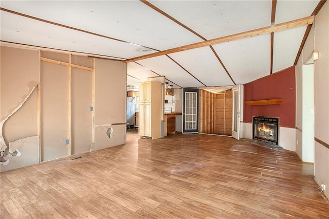 unfurnished living room with a glass covered fireplace, vaulted ceiling with beams, and wood finished floors