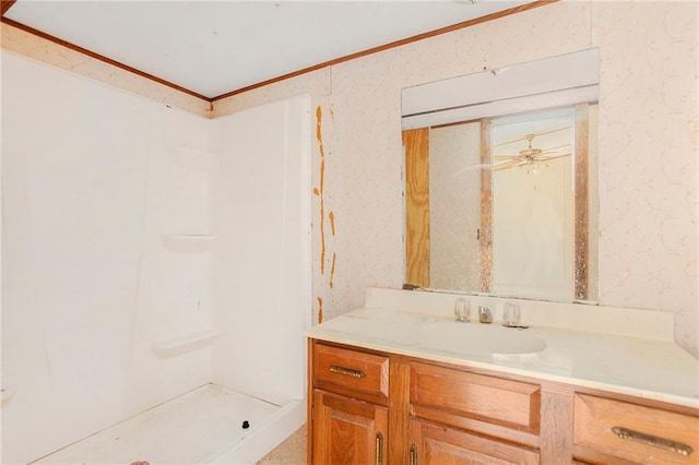 full bathroom featuring a ceiling fan, wallpapered walls, crown molding, a shower stall, and vanity