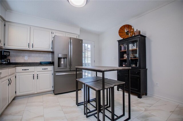 kitchen with white cabinets, stainless steel fridge, backsplash, and crown molding