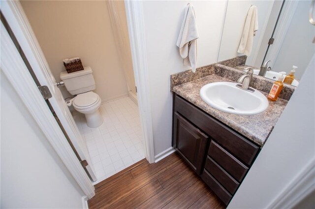 bathroom with hardwood / wood-style floors, vanity, and toilet