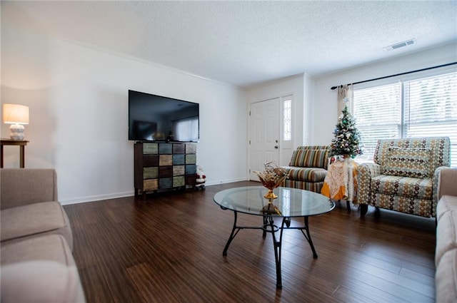 living room with dark hardwood / wood-style floors, ornamental molding, and a textured ceiling