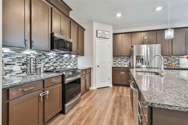 8 Unbridled Way, Newnan, GA 30263 - kitchen with appliances with stainless steel finishes, a sink, backsplash, light wood-type flooring, and light stone counters