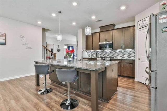 8 Unbridled Way, Newnan, GA 30263 - kitchen featuring stainless steel appliances, light stone countertops, decorative backsplash, a sink, and an island with sink