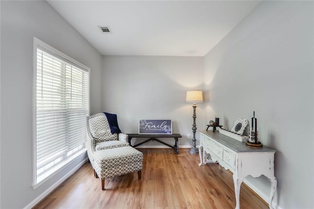 sitting room with light wood-style floors, visible vents, and baseboards