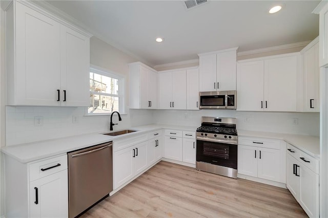 kitchen with appliances with stainless steel finishes, white cabinetry, and sink