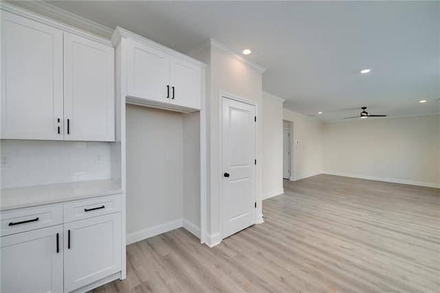 kitchen featuring ceiling fan, backsplash, light hardwood / wood-style floors, white cabinetry, and ornamental molding