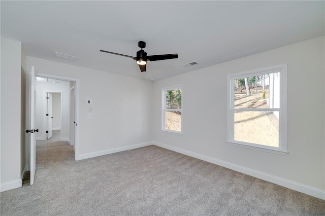 empty room with ceiling fan, light colored carpet, and a wealth of natural light