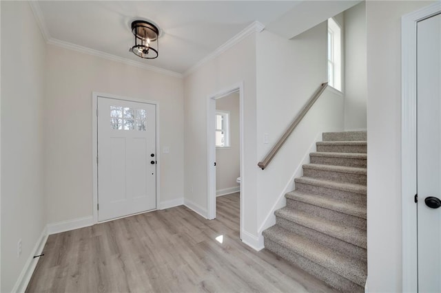 entrance foyer with light wood-type flooring, ornamental molding, and a healthy amount of sunlight