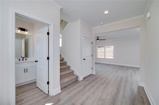 hallway with sink, crown molding, and light hardwood / wood-style flooring