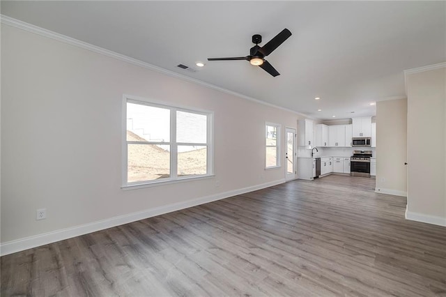 unfurnished living room featuring ceiling fan, ornamental molding, light hardwood / wood-style flooring, and sink