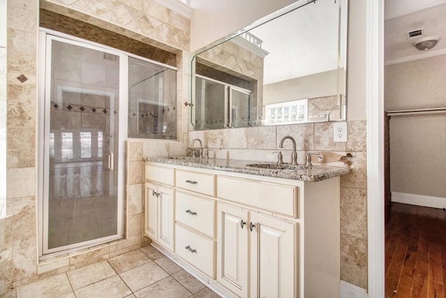 bathroom featuring tile walls, vanity, ornamental molding, a shower with shower door, and tile patterned floors