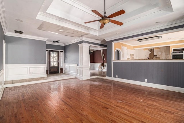 unfurnished living room with dark hardwood / wood-style flooring, ornamental molding, decorative columns, and a raised ceiling