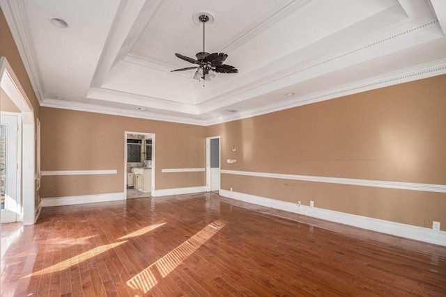 empty room featuring a tray ceiling, wood-type flooring, ornamental molding, and ceiling fan