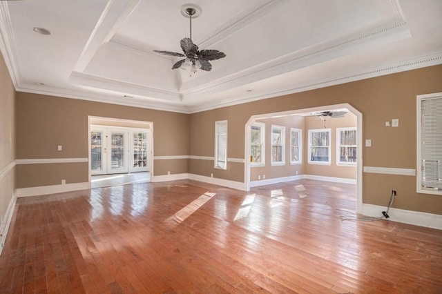 unfurnished living room featuring ceiling fan, wood-type flooring, and a tray ceiling