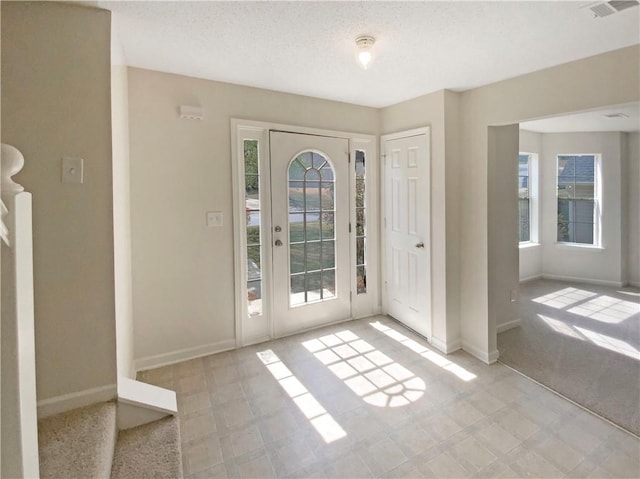 entryway with visible vents, baseboards, and a textured ceiling