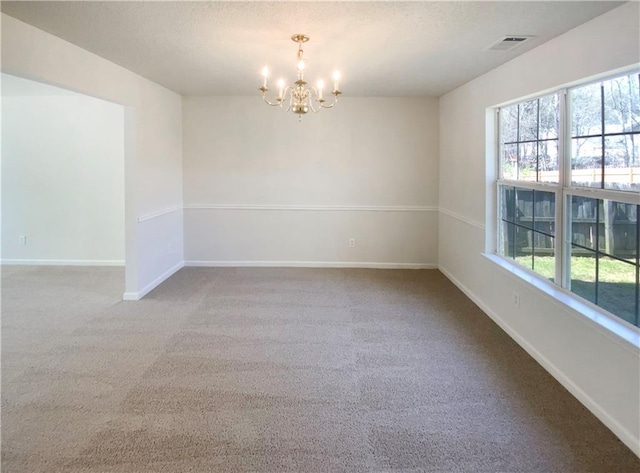 carpeted empty room with plenty of natural light, a notable chandelier, baseboards, and visible vents