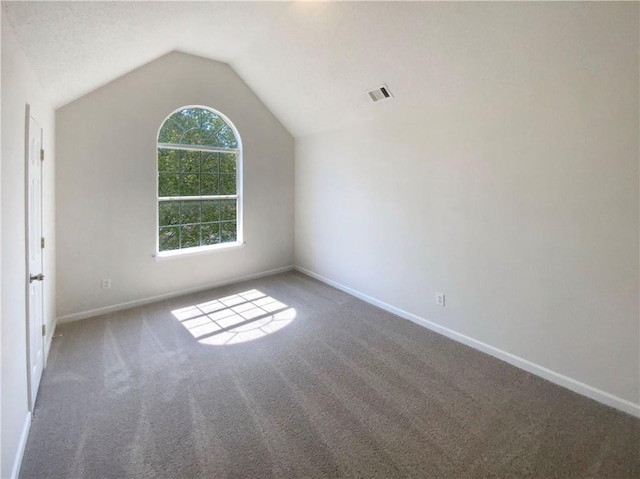 unfurnished room with carpet flooring, baseboards, vaulted ceiling, and visible vents