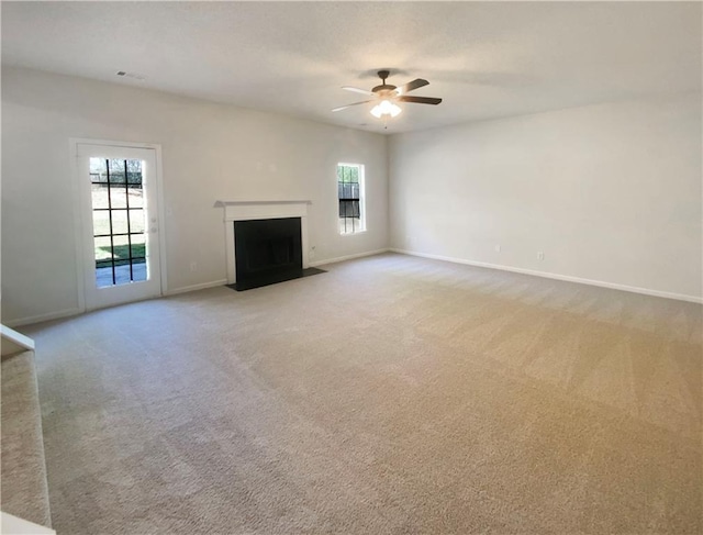 unfurnished living room featuring a fireplace with flush hearth, light colored carpet, baseboards, and a ceiling fan