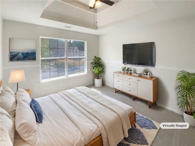 bedroom with a tray ceiling, baseboards, visible vents, and carpet flooring