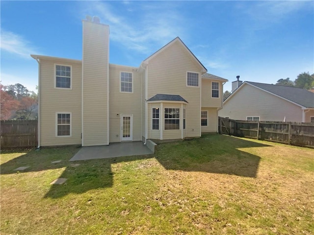 rear view of house featuring a fenced backyard, a chimney, a yard, and a patio